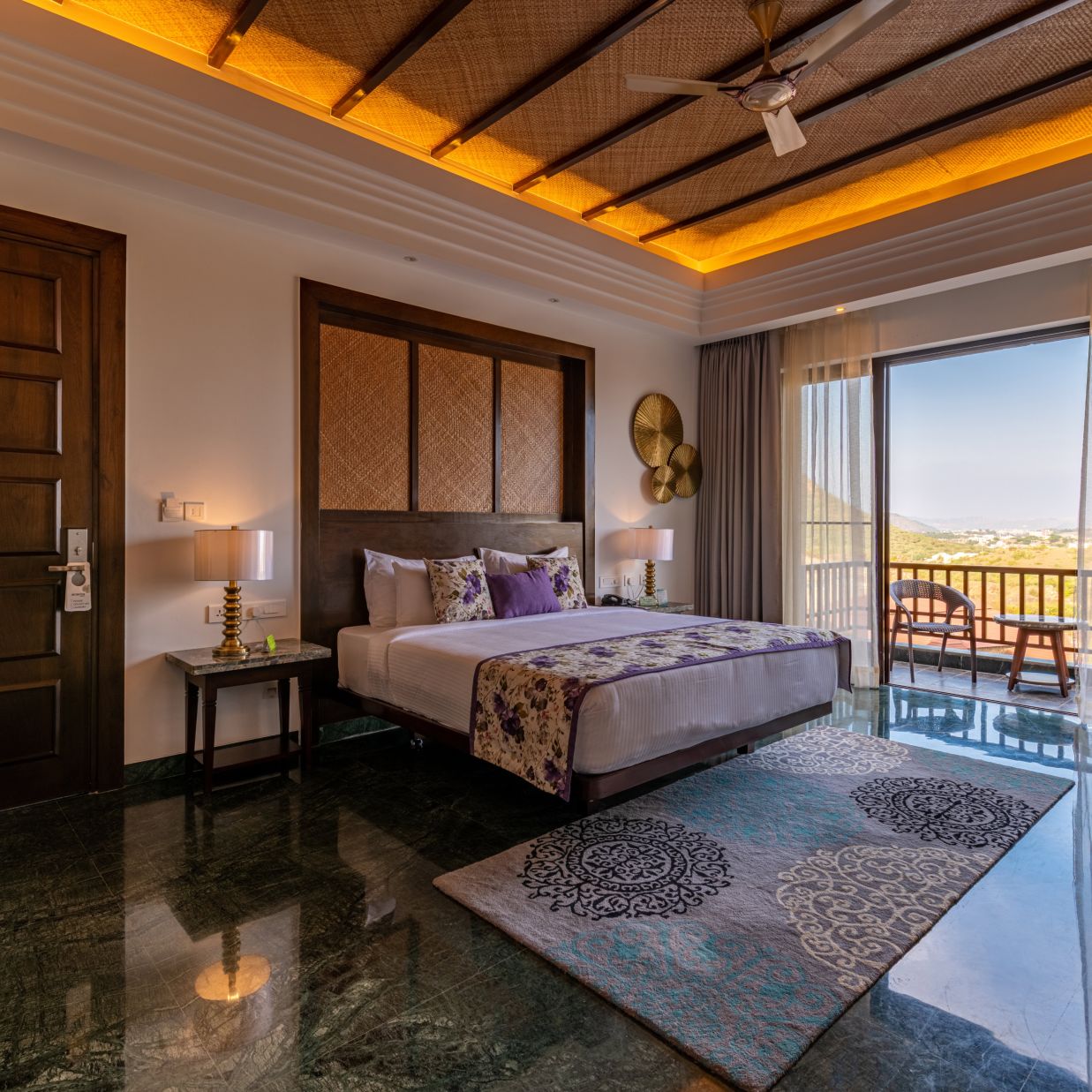 A king size bed with side table, floor to wall windows a balcony at luxury cottage with balcony - The Ananta Udaipur