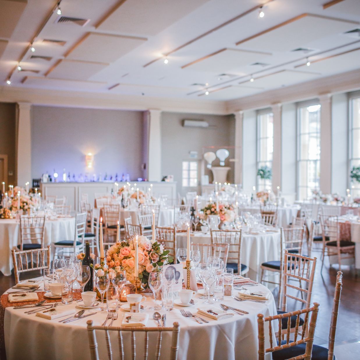 Round tables in scattered in a room with sunlight shining down from the windows