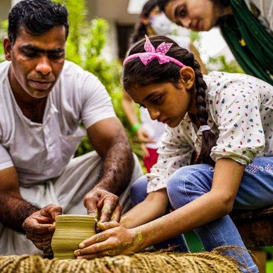 a ceramist teaching a little girl pottery