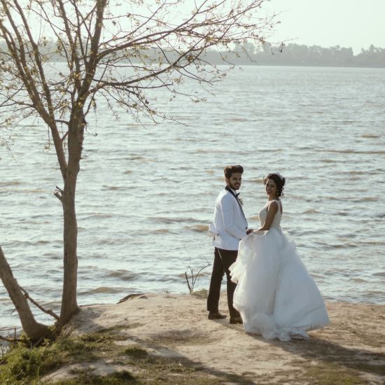 A couple standing by the lake during the day