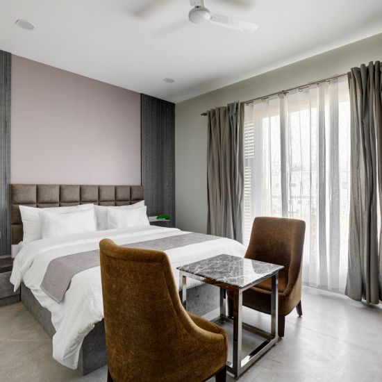 Grey themed Deluxe room with king size bed and brown chairs - The White Moon