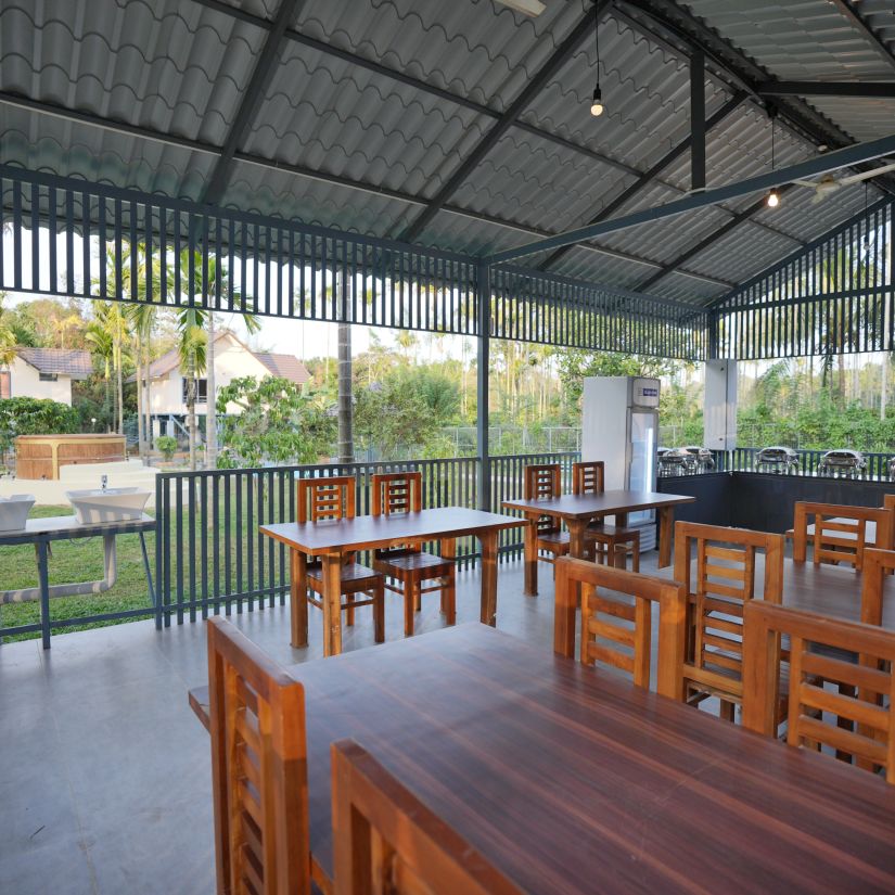 Dining area with tables and chairs with a view of the lush greenery at Feel Free Retreat, Wayanad