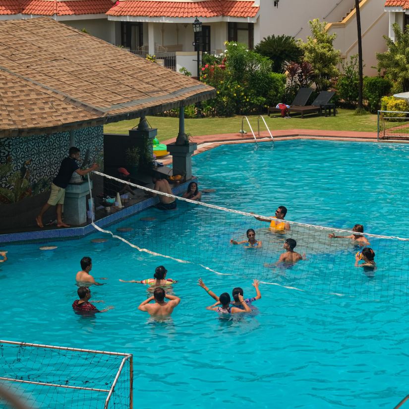 Heritage Village Goa - People playing throwball in the swimming pool while the lifeguard is on duty