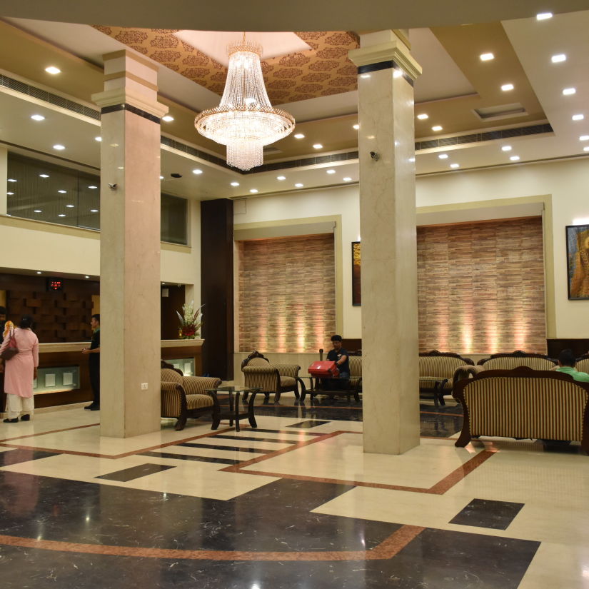 A wide angle view of the lobby with sofa sets, coffee tables and a chandelier on the top | Hotel City Inn, Varanasi