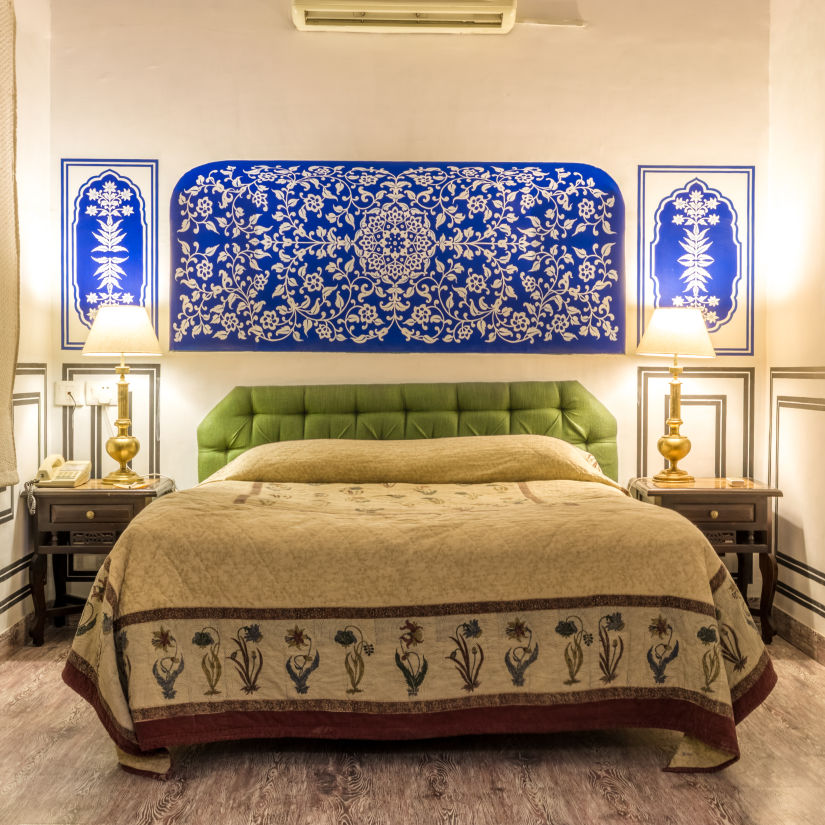 A king bed with lamps on the side table inside deluxe rooms - Mandawa Haveli, Jaipur