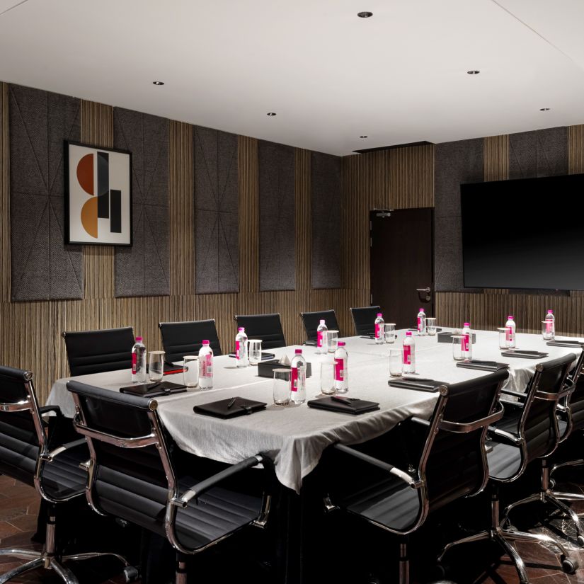 A conference room with dark walls and a long table flanked by chairs - at Parallel Hotel Udaipur