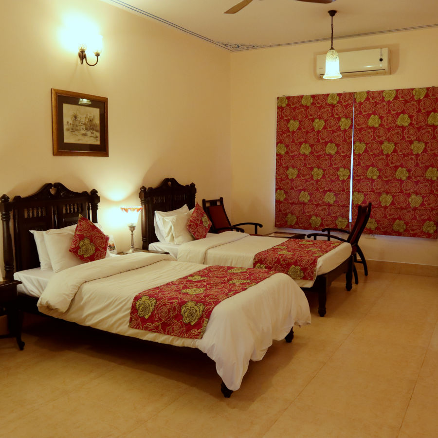 Twin beds with beautiful red bedsheets and red pillow covers at Junior Suite at Suryaa Villa Jaipur