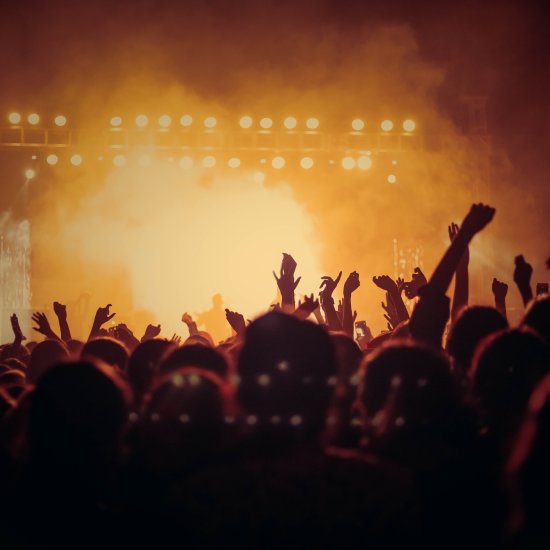 people with their hands raised in the air at a concert at night