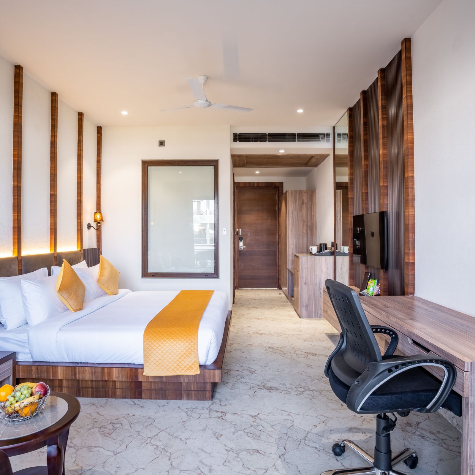 A bedroom with a large bed, a coffee table, a work desk and a revolving chair - Shervani Pebbles & Pines, Corbett