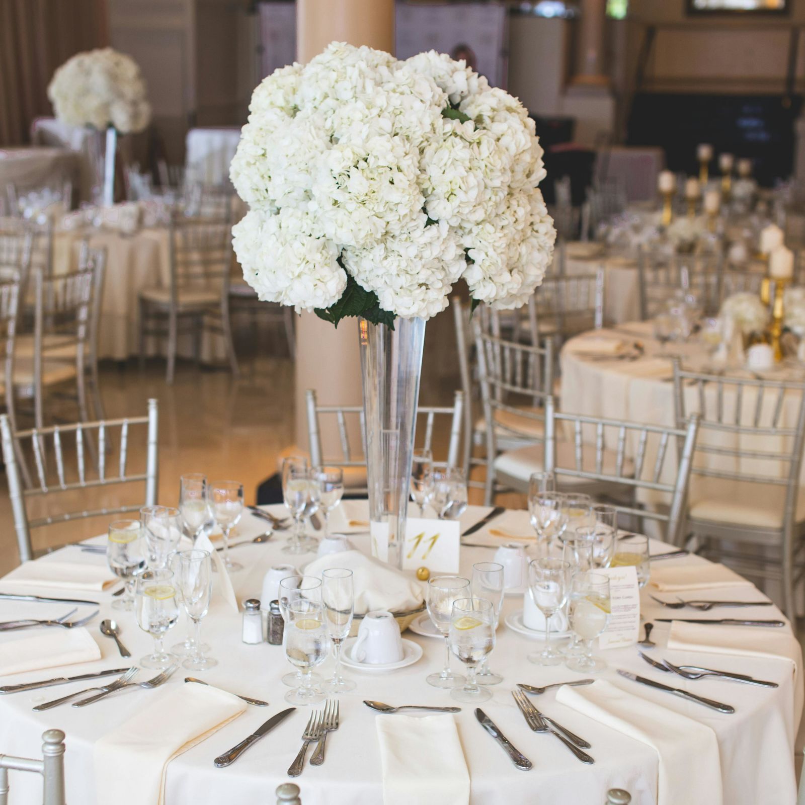 Classically decorated wedding reception table with lush white floral arrangements