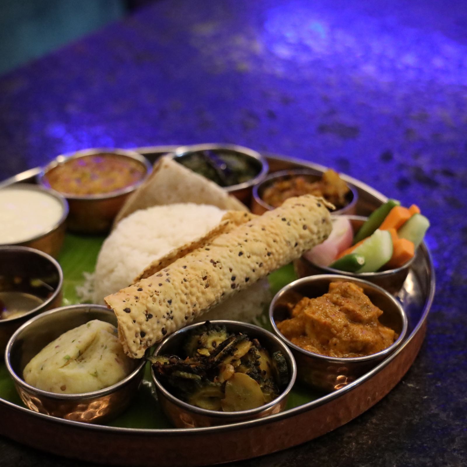 a plated thali with rice, papad and assorted vegetables - Wonderla Bhubaneswar