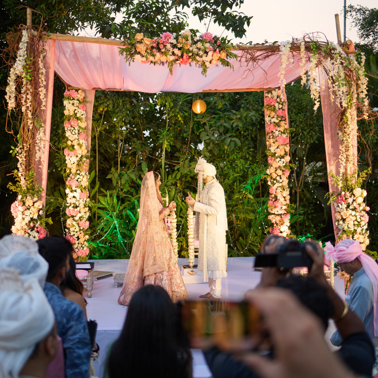 a bride and groom under a canopy during their wedding ceremony with a crowd looking on - Heritage Village Resorts & Spa, Goa