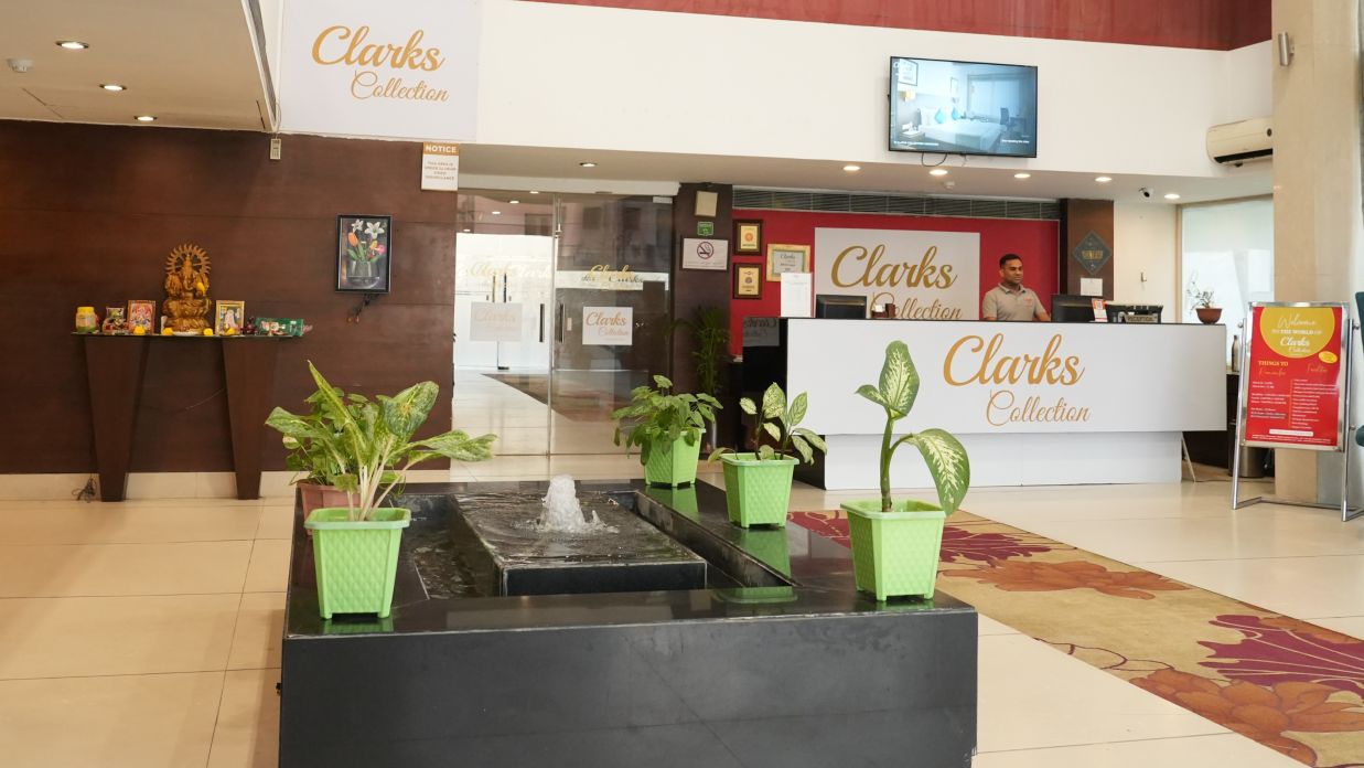 A reception area adorned with plants and a water fountain at Clarks Collection, Bhavnagar