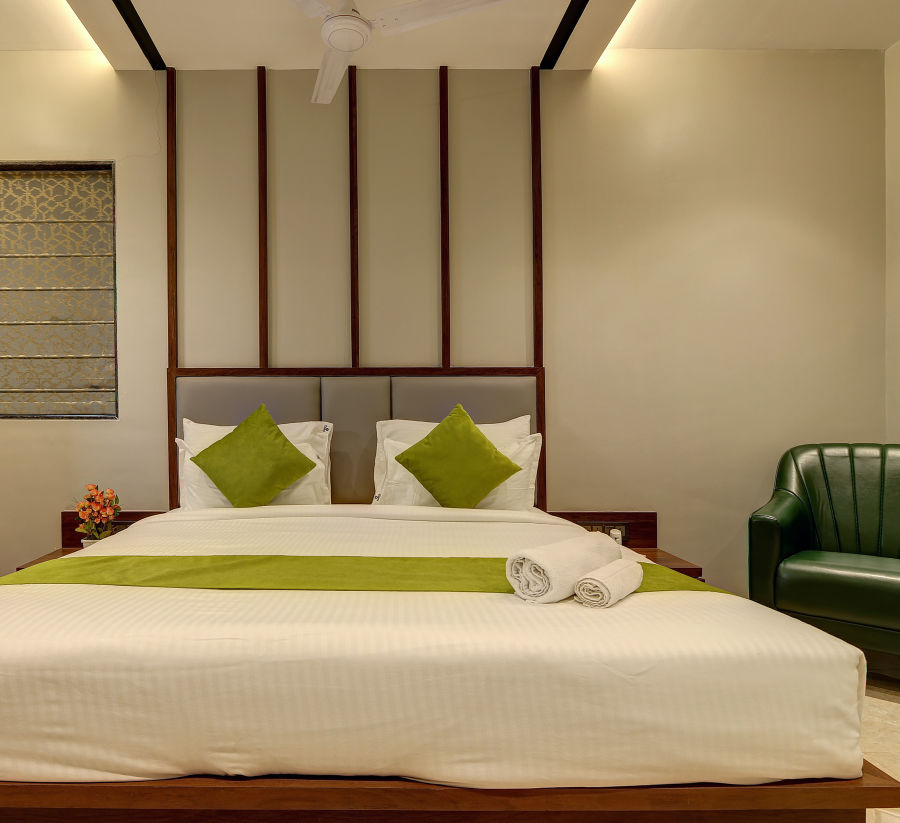 alt-text Double bed with a chair next to it inside Luxury Suite - Fortune House, Magarpatta