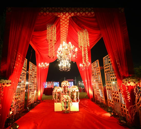 alt-text a wedding venue decked up with red cloth and chandelier in the backdrop of the night