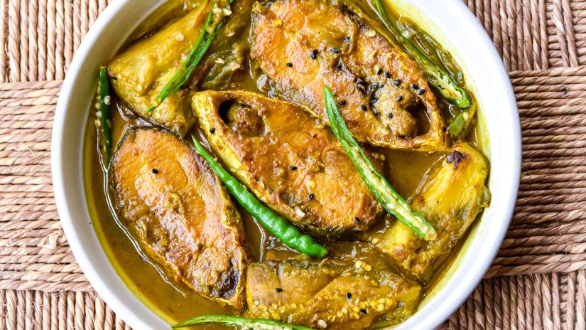 Fish gravy served on a bowl and topped with green chillies.