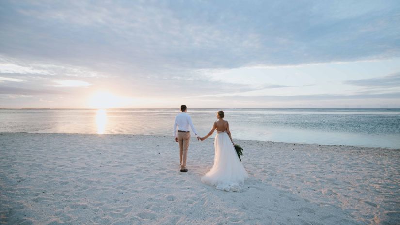 A couple holding hands and walking on a beach