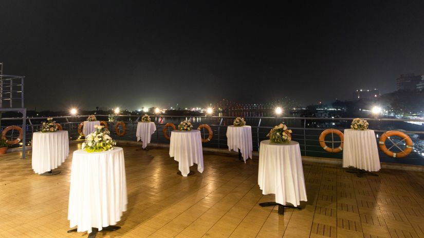 Compass Deck - Rooftop event space at night with tables set for an outdoor gathering, overlooking city lights -  Polo Floatel Kolkata