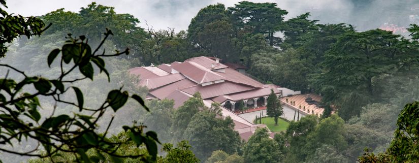 An aerial view of The Claridges Nabha Residence in Mussoorie, surrounded by a dense forest.