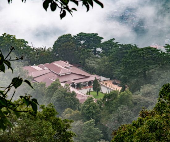 alt-text An aerial view of The Claridges Nabha Residence in Mussoorie, surrounded by a dense forest.