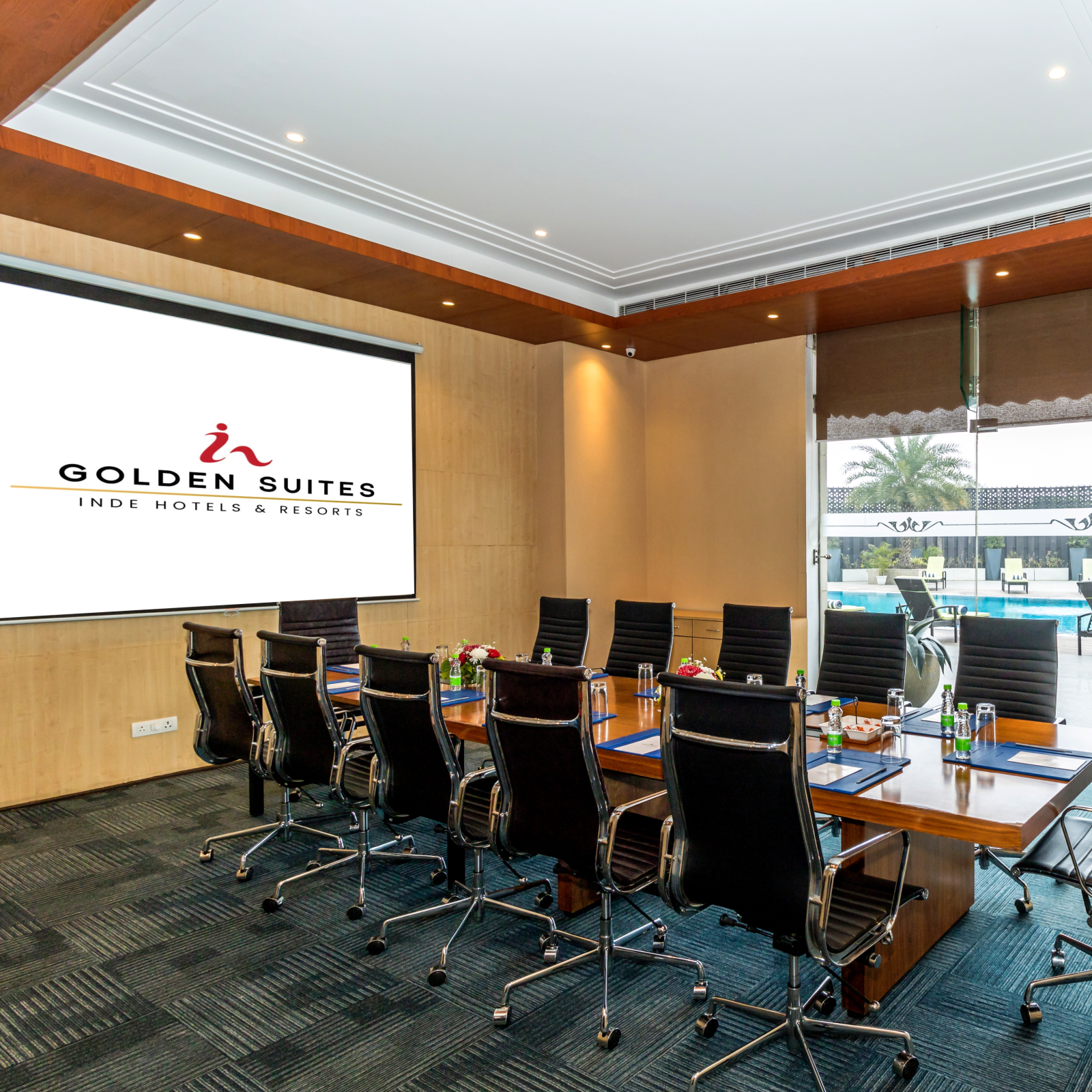 Boardroom with chairs round the table and a screen at Golden Suite