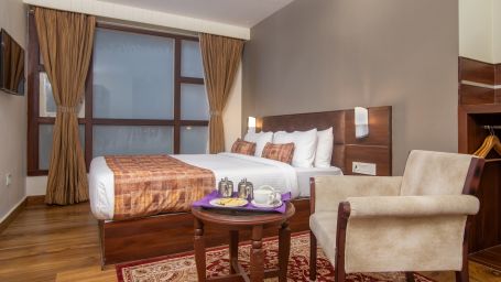 An armchair, a tea table and a double bed in the Deluxe Double room at Hotel Sumi Vista T.V Tower 