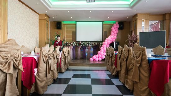 A party hall with round tables and chairs and a projector