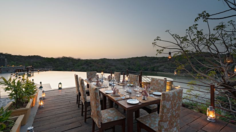 A table for six set on a doc with cutlery and glasses already set on it on the dock - Chunda Shikar Oudi, Udaipur