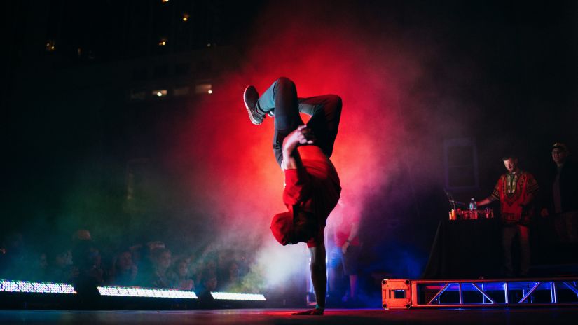 a person dancing on the stage while doing a one arm hand stand