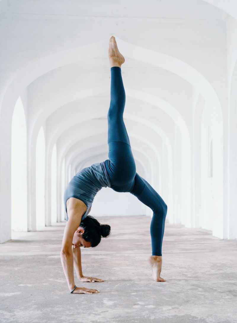 a woman performing a yoga pose in a corridor of a white building