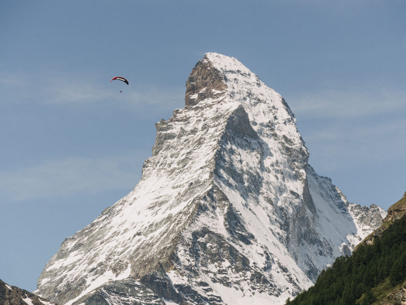 Snow capped mountains with a person paragliding above it