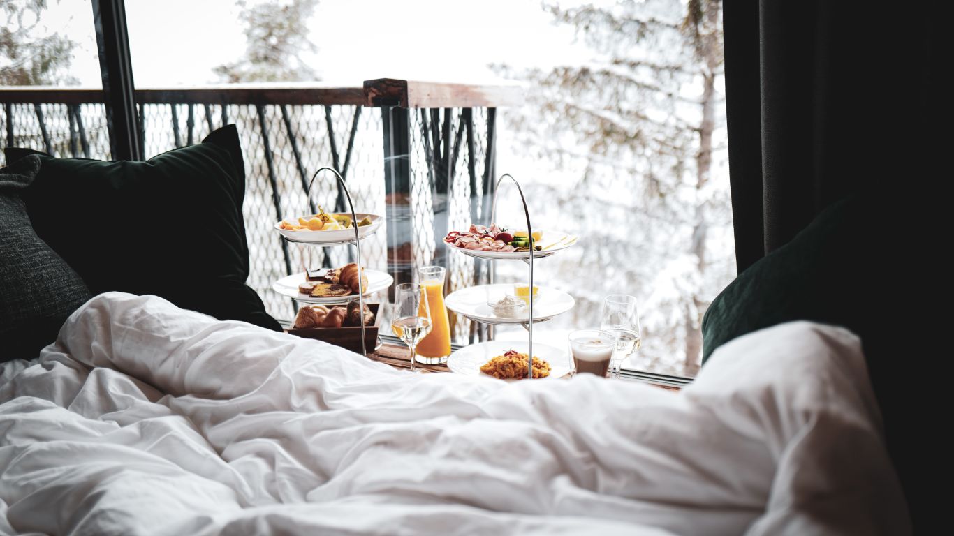 A messy bed with window in the background showing trees