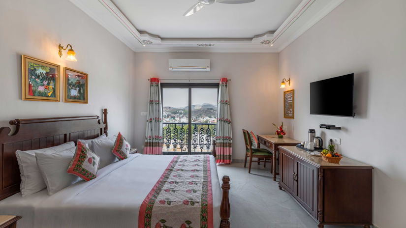 An overview of the suite with a king bed, tv, ac and balcony at Superior Room - Maan Vilas by Stone Wood, Udaipur