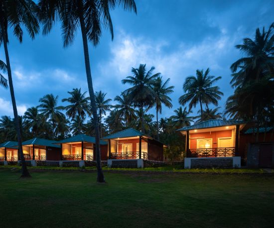 alt-text a far out view of cottages with coconut trees and dark sky in the background