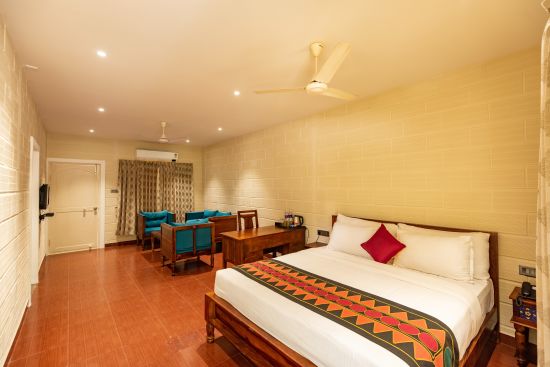 alt-text a double bed, sofas and a fan on the ceiling inside the suite at Ibex River Resort, Pollachi