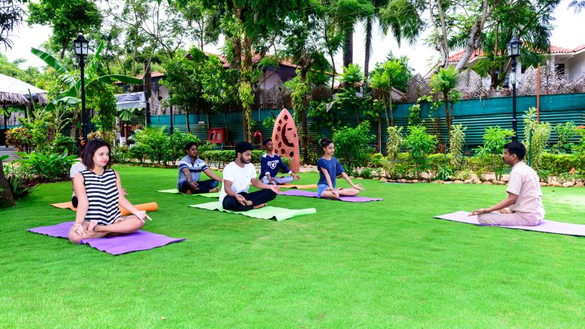 Guests doing Yoga on yoga mats kept on a lawn at our resort with activities in South Goa - Heritage Village, Goa