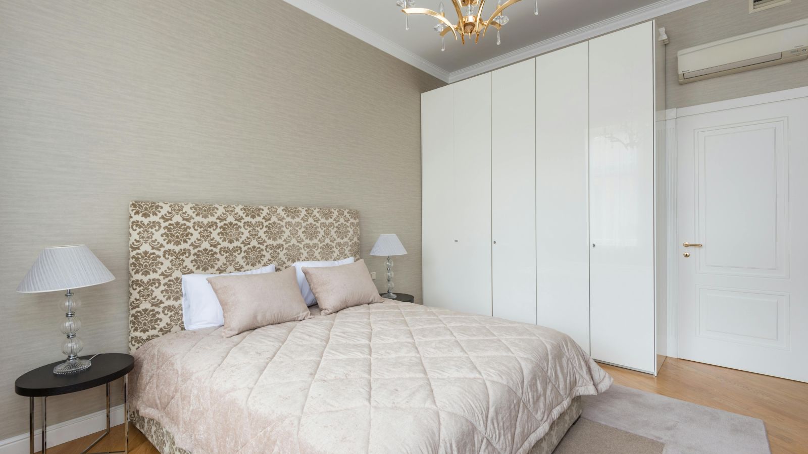 image of a bedroom with a cosy queen size bed with white panel wardrobe at one corner of the room