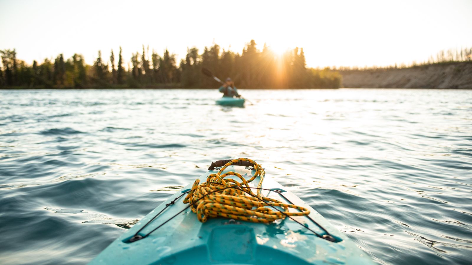 The bow of a boat is visible navigating through a lake - Kumarakom Kayaking