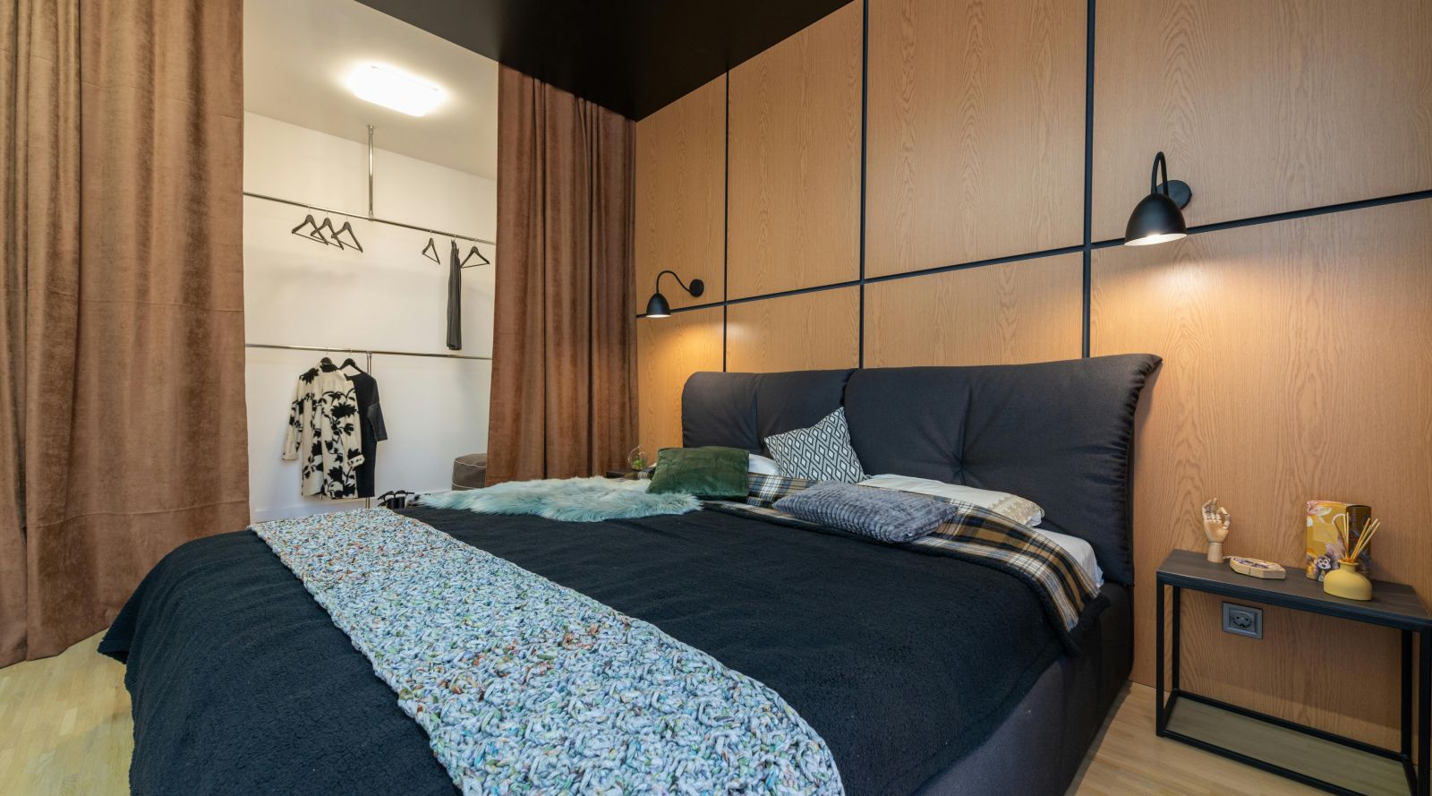 image of a bedroom featuring a plush king size bed with dark blue covers and bright lights beside it with modern interiors