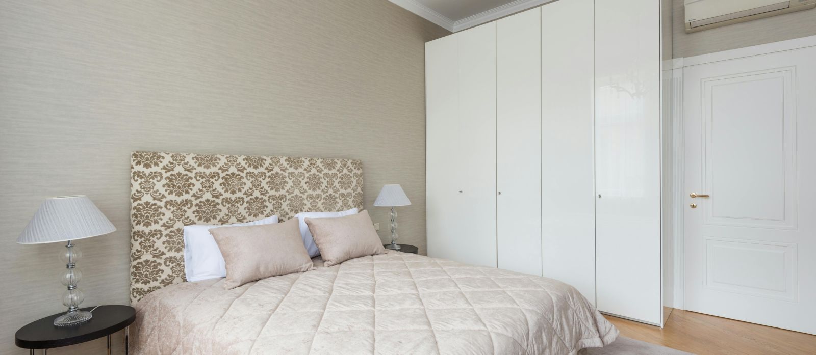 image of a bedroom with a cosy queen size bed with white panel wardrobe at one corner of the room