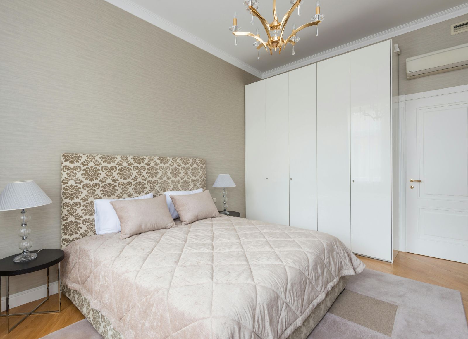 image of a bedroom with a cosy queen size bed with white panel wardrobe at one corner of the room