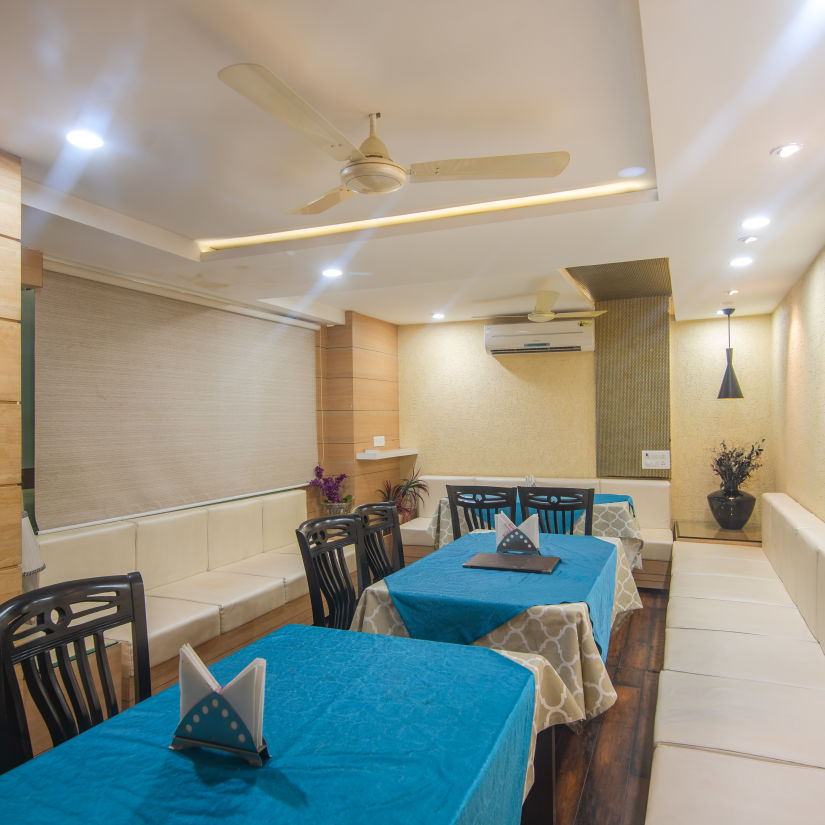 A restaurant with several tables and chairs - Morya Regency, Bhopal