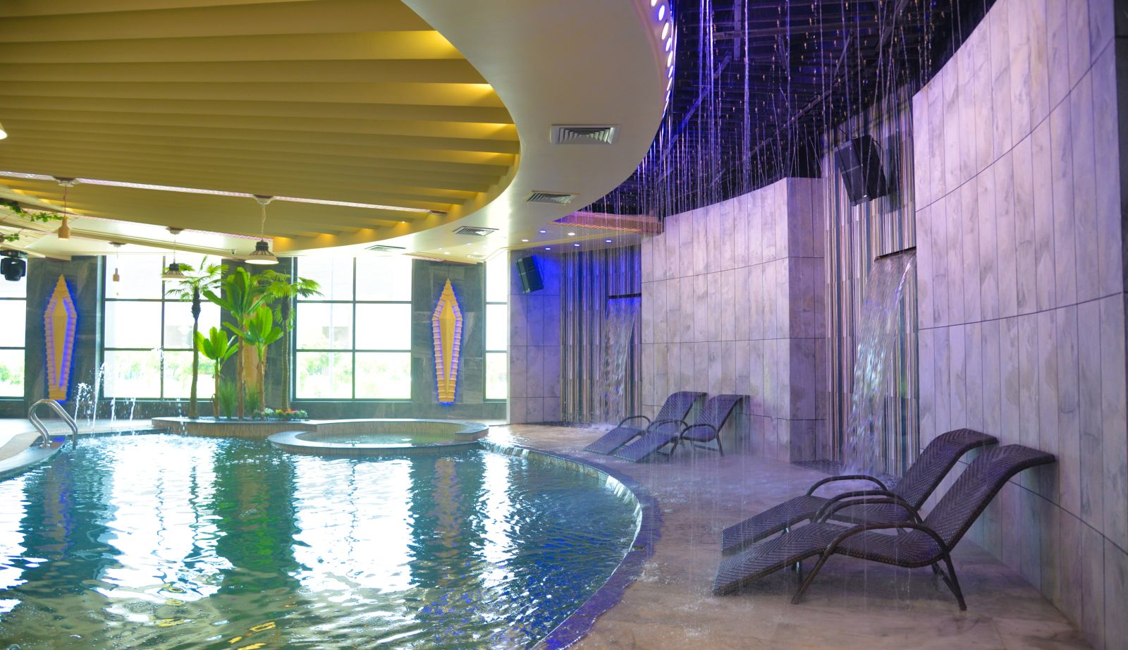 An indoor swimming pool with waterfall and rainy effects