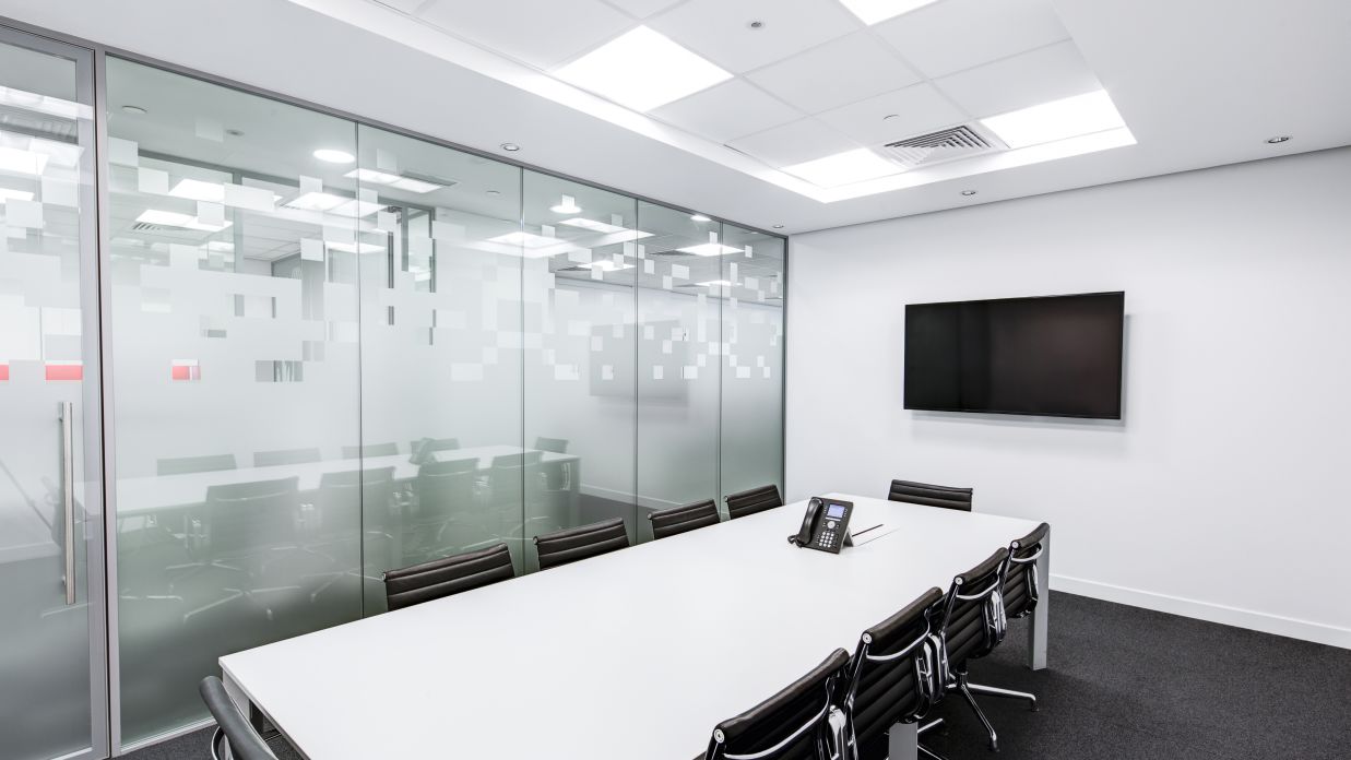 A meeting room with a white rectangular table and desk chairs