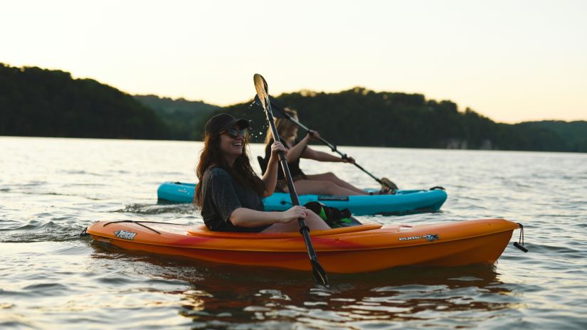 two women kayaking together with land in the background having forest cover