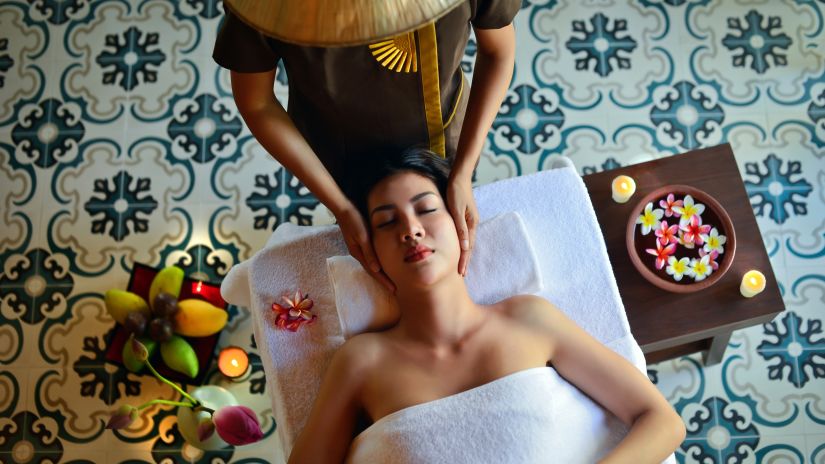 a woman getting a spa treatment from a masseuse with a bowl of water and flowers inside it