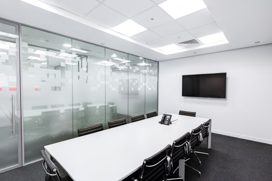 alt-text A meeting room with a white rectangular table and desk chairs