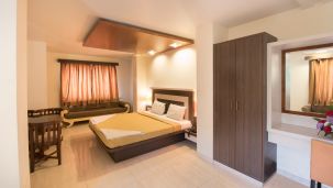 Hotel Vaikunth by Adamo - the bed placed in the bedroom along with a seating area opposite the bed