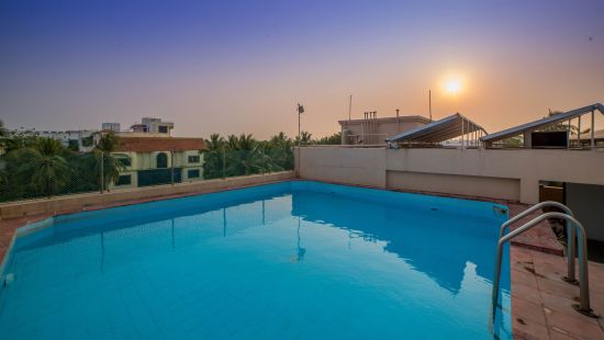 swimming Pool with the sun setting in the backgroundat Raj Park Hotel in Alwarpet, Chennai