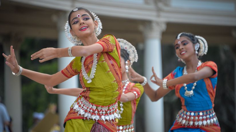 Three ladies wearing sarees and dancing during the day | Odissi dance